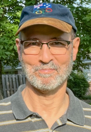 Snapshot of the author outdoors. He's also wearing glasses.